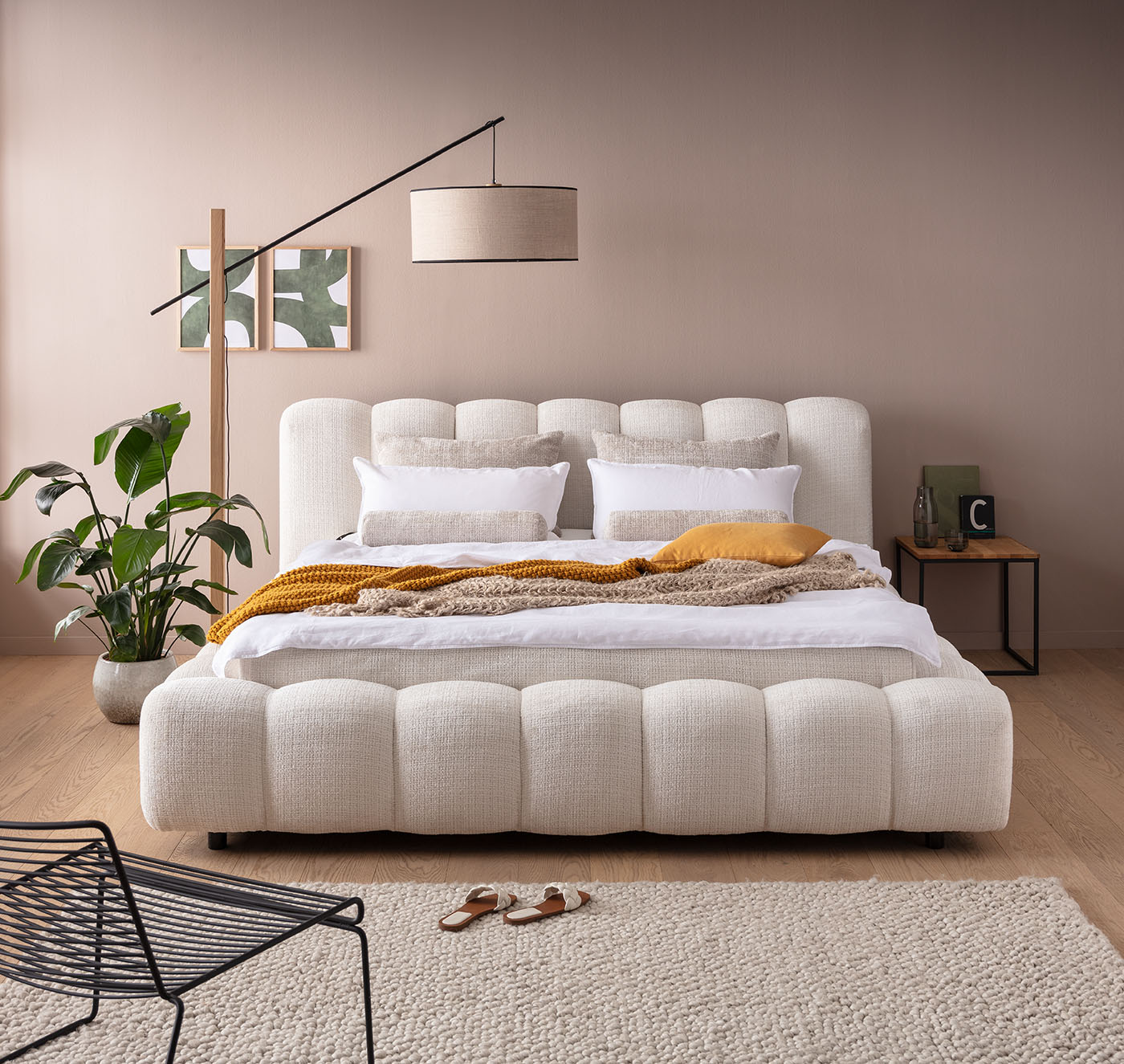 Bett mit bauchiger, breiter Rillenoptik in Schlafzimmer mit hellbrauner Wand