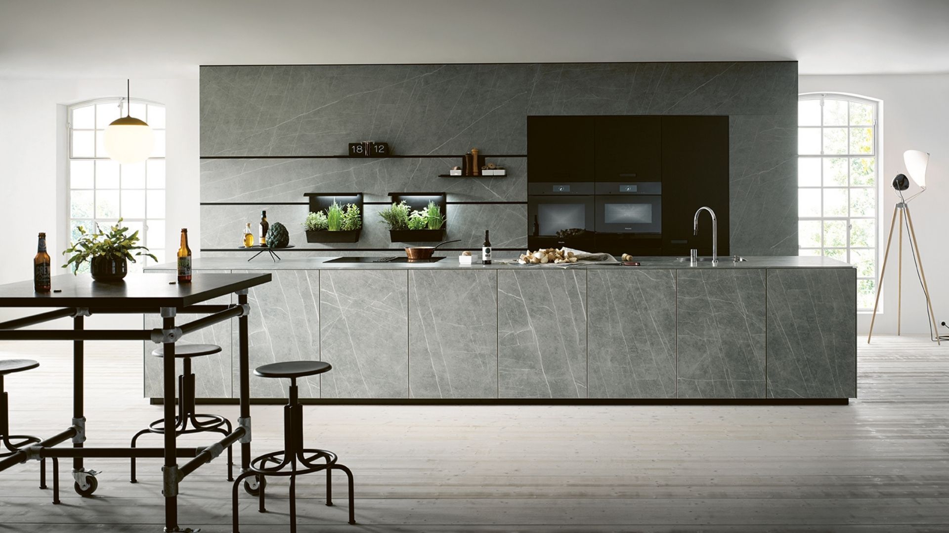 Moderne Designküche in Grau mit Kochinsel und offenen Regalen, kombiniert mit hohem Bartisch in großzügigem Raumkonzept.