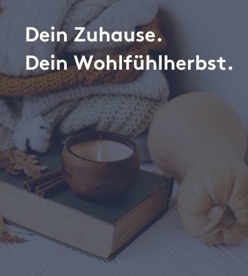 Herbstliche Wohlfühlatmosphäre mit Kürbissen, einem brennenden Duftkerzenglas auf einem Buch, Zimtstangen, getrockneten Blättern und einer grob gestrickten Decke im Hintergrund. Text: ‚Dein Zuhause. Dein Wohlfühlherbst