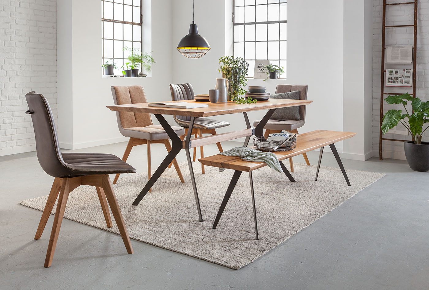 Der Industrial Chalet Stil bringt Tischplatte in Holzoptik und schwarze Raumakzente wie eine Gitteroptik im Essbereich zusammen. Eine Leiter kann als Highlight zum Zeitungsständer umfunktioniert werden