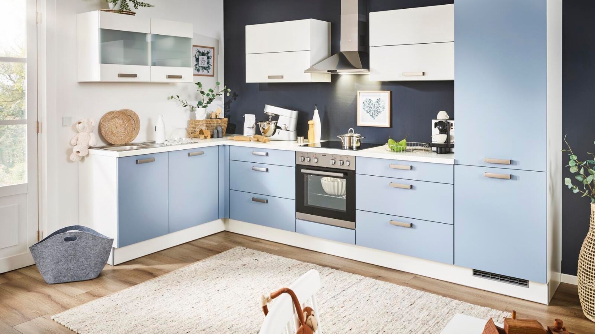 L-förmige Küche mit hellblauen Fronten, weißen Oberschränken und integriertem Backofen – gemütlich eingerichtet im modernen Landhausstil.