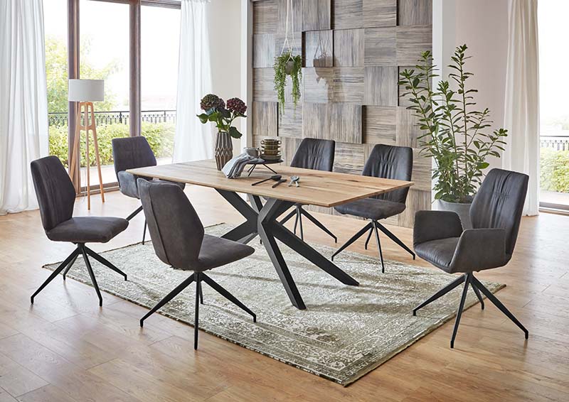 Eine Wand in Holztäfelchen-Optik und dunkle Stühle mit leicht kantigem Umriss prägen ein modernes Chalet-Stil-Esszimmer