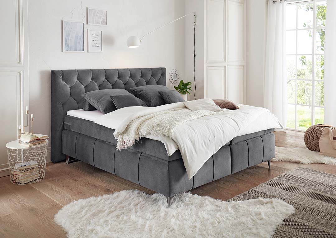 Kunstfell und Kuscheldecken prägen Dein Chalet-Stil-Schlafzimmer. Ein rundes Wandornament mit verschlungenen Formen fügt eine Boho-Style-Note hinzu. Derweil erzeugt ein Polsterbett in stilvollem Grau glamouröses Flair
