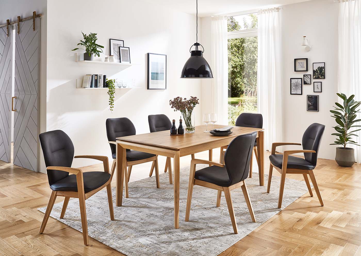 Stühle mit dunklen Bezügen, um einen Esstisch stehend, verleihen dem Landhausstil eine moderne Note