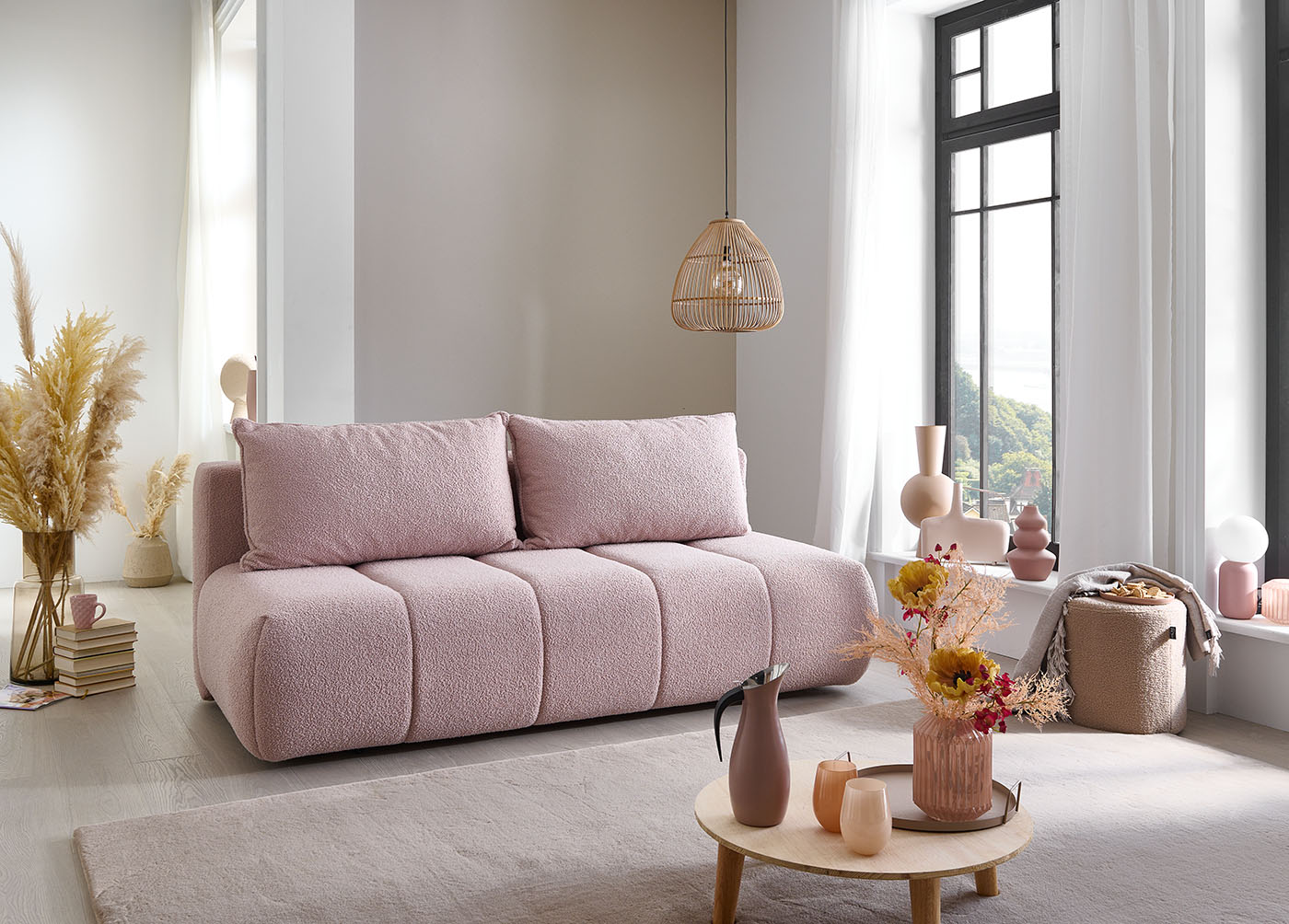 Altrosafarbenes Sofa in kissenartigem Look mit Rillenoptik umgeben von Deko in Trockenpflanzenoptik