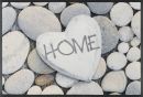 Herzförmiger Stein mit Aufschrift „HOME“ auf runden Kieselsteinen, Symbol für Zuhause und Geborgenheit.