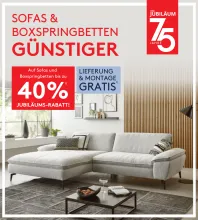 40 % Rabatt auf Sofas und Boxspringbetten Werbebanner mit grauem Ecksofa in modernem Wohnzimmer; Text: „Sofas & Boxspringbetten günstiger! 40 % Jubiläums-Rabatt“, dazu Hinweis auf gratis Lieferung & Montage.