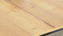 Nahaufnahme einer hellen Holz-Tischplatte mit natürlicher Maserung und feinen, dunklen Ästen, moderne Optik.