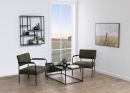 Modernes Wohnzimmer mit zwei grünen Sesseln, Couchtisch, Wandregal, Bild und großem Fenster mit Ausblick.