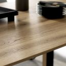 Schöner Wohnen Esstisch Cross Nahaufnahme eines modernen Holztisches mit natürlicher Maserung, schwarzem Geschirr und minimalistischer Dekoration.