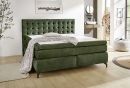 Grünes Boxspringbett mit gestepptem Kopfteil, weißer Bettdecke und Kissen, modernes Schlafzimmermöbel.