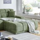 Grünes Ecksofa mit Kissen und Decke im modernen Wohnzimmer, Tageslicht, dekorative Vase am Fenster.