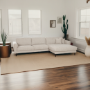 Modernes Wohnzimmer mit beigem Ecksofa, Holzboden, großen Fenstern, Zimmerpflanzen und minimalistischer Dekoration.