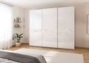 Moderner weißer Kleiderschrank mit Marmor-Design in hellem Schlafzimmer, Holzboden und Zimmerpflanze.