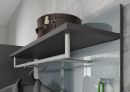 Moderne Garderobe mit grauer Ablage, Kleiderstange, braunem Koffer und Jacke vor Betonwand.