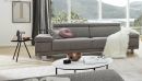 Modernes graues Sofa im Wohnzimmer mit Kissen, Decke, Couchtisch, Dekoration und Panoramablick auf die Natur.