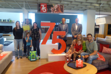 Gruppenfoto in der Möbel RIEGER Ausstellung: Erwachsene und Kinder stehen und sitzen rund um eine große rote „75“ zur Feier des 75-jährigen Jubiläums. Im Hintergrund Sofalandschaften und Jubiläums-Deko.