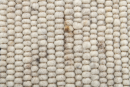 Nahaufnahme einer beigen Wollteppich-Oberfläche mit grober, strukturierter Webart und natürlicher Faseroptik.