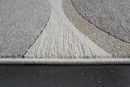 Moderner Teppich in Grau, Beige und Weiß mit abstraktem Muster auf dunklem Boden, Nahaufnahme der Struktur.
