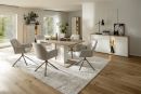 Modernes Esszimmer mit Holztisch, sechs weißen Stühlen, Sideboard, Regalen und großen Fenstern im Tageslicht.
