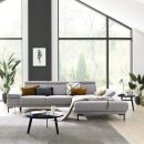 Modernes Wohnzimmer mit grauem Sofa, großen Fenstern, Zimmerpflanzen und stilvoller, heller Einrichtung.