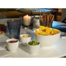 Schale mit Nachos, drei Dips, Salzstangen, Glas Wasser und Kerze auf einem weißen Tisch im Wohnzimmer.