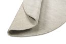 Beiger Teppich aus Naturfaser, Detailaufnahme der umgeschlagenen Ecke auf weißem Hintergrund.