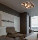 Modernes Wohnzimmer mit Ledersessel, abstraktem Wandbild und geometrischer LED-Deckenleuchte bei Tageslicht.