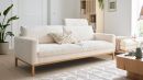 Modernes, cremefarbenes Sofa im skandinavischen Stil in hellem Wohnzimmer mit Pflanze und Holzmöbeln.