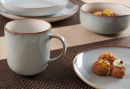 Graue Keramiktasse und Teller mit Gebäck auf gedecktem Holztisch, modernes Geschirr-Set, Frühstücksszene.