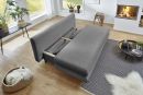 Graues Schlafsofa im modernen Wohnzimmer mit Kamin, Holzboden, Pflanzen und großen Fenstern bei Tageslicht.