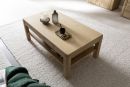 Moderner Couchtisch aus hellem Holz auf Teppich, dekoriert mit Kerzen, Vase, Tasse und Snack im Wohnzimmer.