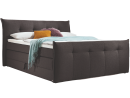 Modernes Boxspringbett in Dunkelgrau mit Kopf- und Fußteil, dekoriert mit Kissen und Tagesdecke.