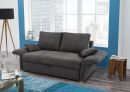 Graues Sofa im modernen Wohnzimmer mit großen Fenstern, Holztisch, Stehlampe und blauem Teppich.
