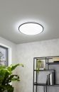Moderne LED-Deckenleuchte leuchtet in hellem Raum mit Regal, Pflanzen und Fenster, energiesparende Beleuchtung.
