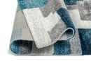 Moderner Teppich mit geometrischem Muster in Blau, Grau und Weiß, weiche Oberfläche, Detailansicht der Kante.