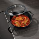 Fischfilets in Tomatensauce mit Karotten in einer schwarzen Pfanne auf einem Induktionskochfeld.