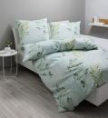 Bettwäsche-Set mit grünem Pflanzenmuster auf hellblauem Hintergrund in modernem, hellen Schlafzimmer.
