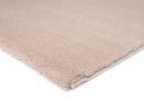 Beiger Hochflor-Teppich auf weißem Hintergrund, weiche Oberfläche, modernes Wohnaccessoire, gemütliche Optik.