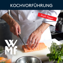 Koch schneidet frischen Lachs bei WMF Kochvorführung, Profi-Tipps, frische Kräuter, professionelle Küche.