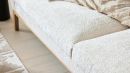 Nahaufnahme eines modernen Sofas mit weichem, cremefarbenem Bouclé-Stoff und dekorativen Kissen im Wohnzimmer.