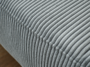 Nahaufnahme eines grauen Cordstoff-Polstermöbels mit weicher, gerippter Struktur und modernem Design.