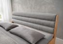 Bett BE-0823 Hellgrau 180 x 200 cm Modernes Bett mit grauem, gepolstertem Kopfteil, Holzrahmen und grauer Bettwäsche in hellem Schlafzimmer.
