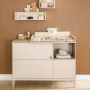 Beige Wickelkommode mit Kuscheltier, Babyutensilien und Regalen vor brauner Wand im modernen Kinderzimmer.