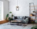 Modernes Wohnzimmer mit grauem Sofa, Holztisch, Zimmerpflanzen, Regal und heller, minimalistischer Einrichtung.