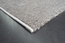 Grauer Teppich auf dunklem Boden, Nahaufnahme der Teppichkante, moderner Wohnstil, hochwertige Textur.