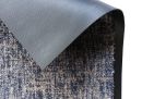 Nahaufnahme einer rutschfesten Teppichunterlage auf blau-grauem Teppichboden, Detailansicht Ecke.