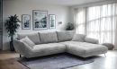 Graues Ecksofa im modernen Wohnzimmer mit großen Fenstern, Wandbildern, Teppich und Zimmerpflanze.