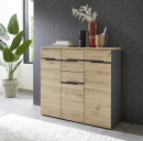 Moderne Kommode aus Eiche mit Dekoration, Pflanze und Tageslicht, vor dunkler Wand im Wohnzimmer.