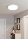 Moderne LED-Deckenleuchte leuchtet Flur mit weißen Wänden, Dekobildern und Holzregal mit Pflanze aus.